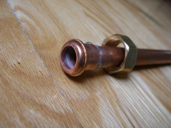 Round half of the re-makeable coupling soldered to the short copper pipe